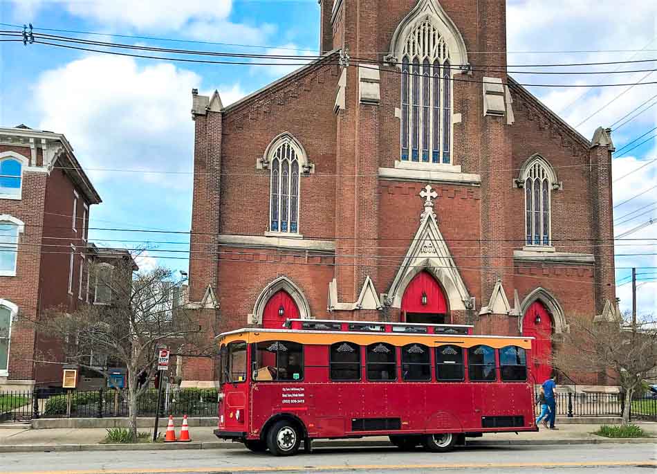 Old Fashioned Express Louisville Trolley tour in front of a historic church in NuLu