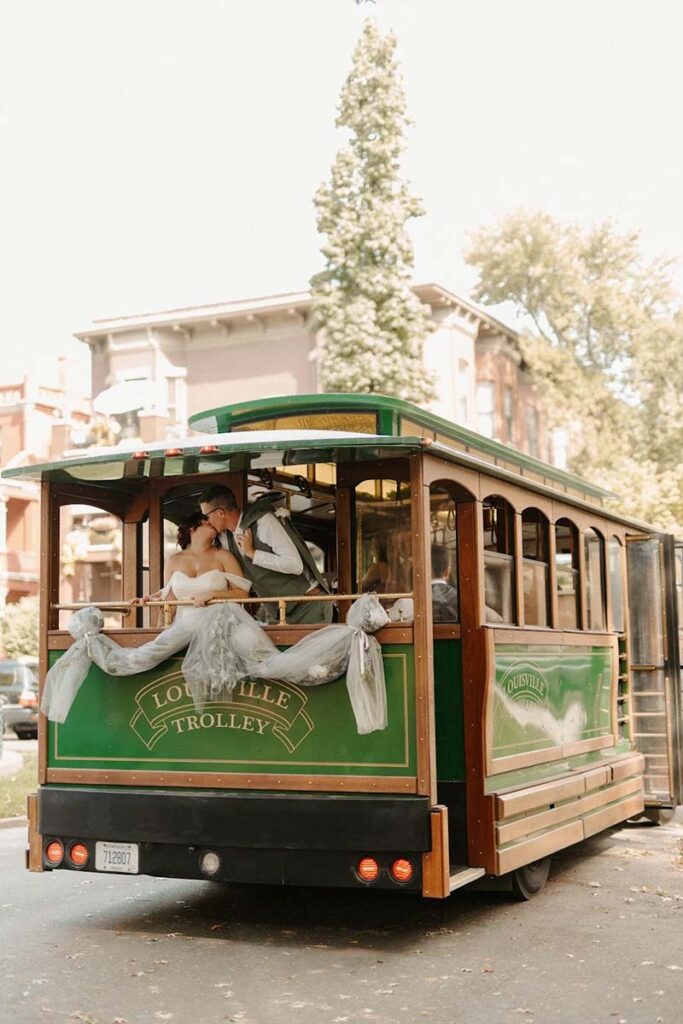 Bride and groom kiss on the balcony of Louisville Toonerville Trolley private wedding charter transportation in Louisville Kentucky