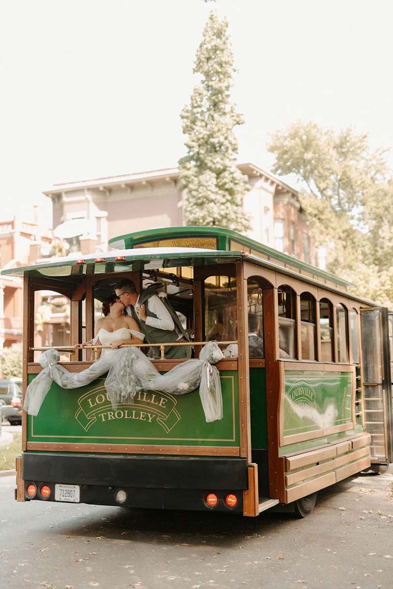 Bride and groom kiss on the balcony of Louisville Toonerville Trolley private wedding charter transportation in Louisville Kentucky